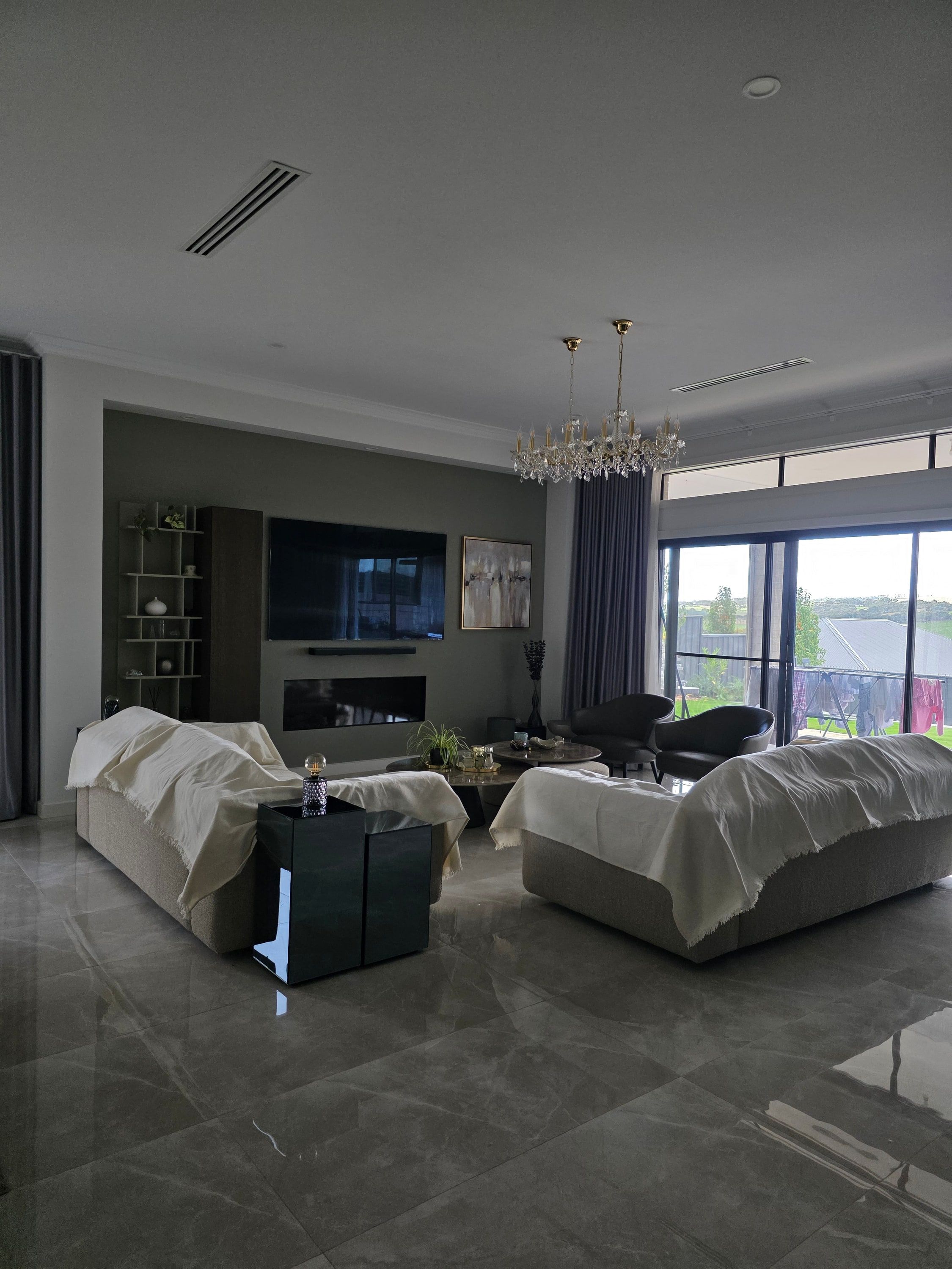 Spacious open-plan living room with polished tile floors, a chandelier and floor-to-ceiling windows in an Adelaide Hills home